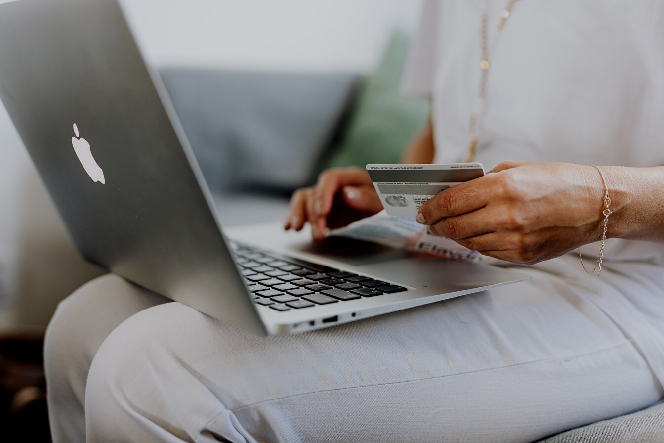 Person Using a Macbook and Holding a Credit Card